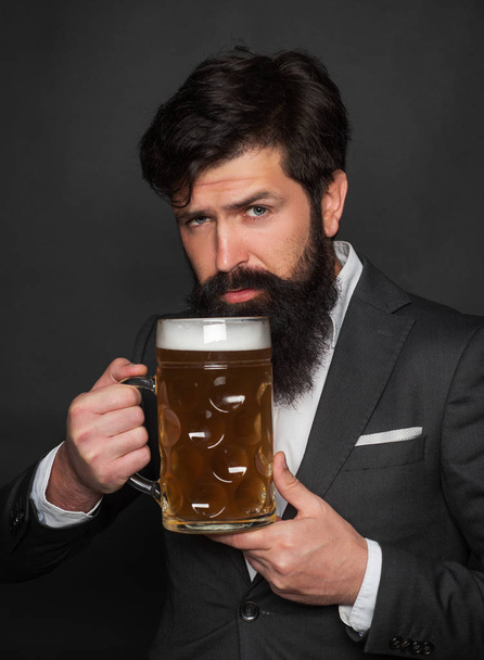 The celebration oktoberfest festival concept. Emotional funny bearded drunk hipster holds craft bottled beer. Germany - Bavaria. Bearded man with a glass of beer. - Фото, изображение