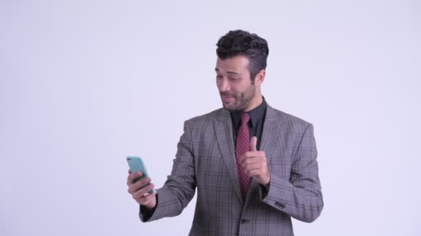 Happy bearded Persian businessman video calling and showing phone - Filmati, video
