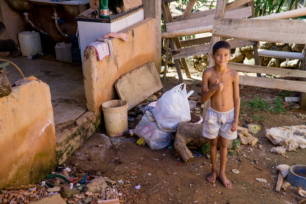 Planaltina, Gois, Βραζιλία-27 Απριλίου, 2019: ένα νεαρό αγόρι που στέκεται έξω από το σπίτι του στην φτωχή κοινότητα της Πλάναλτινα - Φωτογραφία, εικόνα
