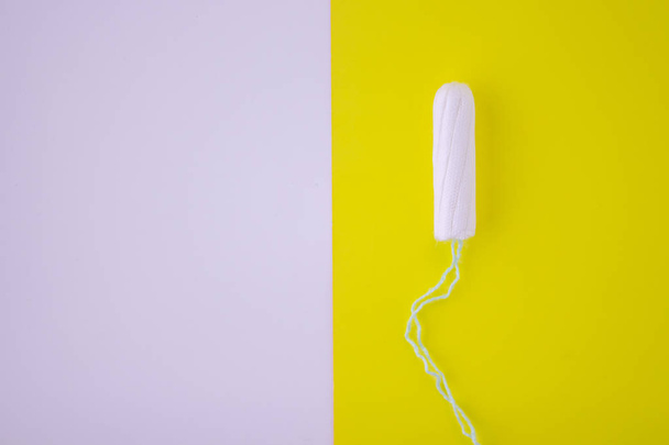 One swab with cotton on a yellow background. The concept of the period of the menstrual cycle. Top view, flat lay. - Foto, Bild