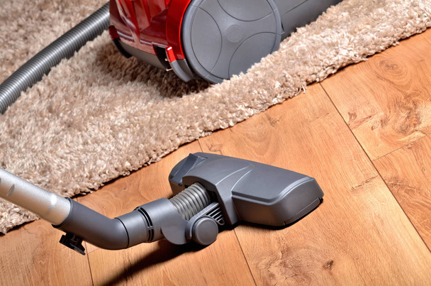 Vacuum cleaner on floating floor and shaggy carpet - Фото, зображення