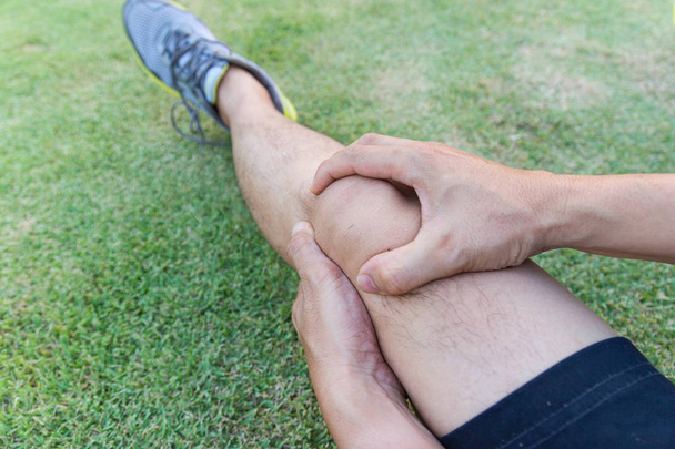 Ścięgna kolana stawów na nodze mężczyzny z ćwiczeń na stadionie.   - Zdjęcie, obraz