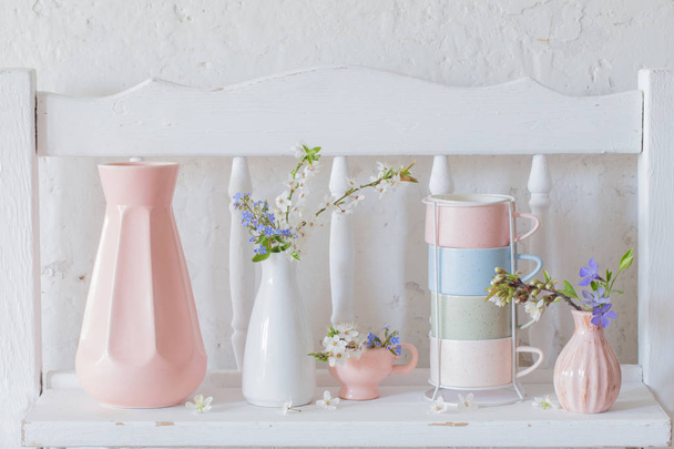 cups and vases with spring flowers on vintage wooden white shelf - Foto, Bild