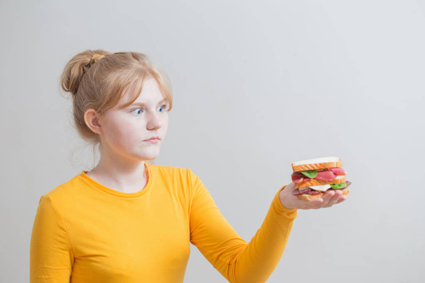 teen girl with  sandwich on gray background  - Foto, Imagem