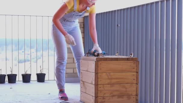una donna su una terrazza fa un lavoro non femminile - fa un foro con un cacciavite in una scatola di legno
 - Filmati, video