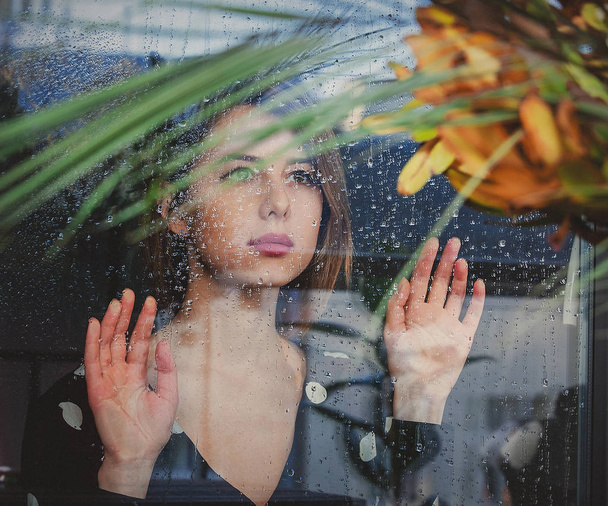 młoda smutna kobieta przy mokrym oknie po tym, jak deszcz przegapił plan - Zdjęcie, obraz