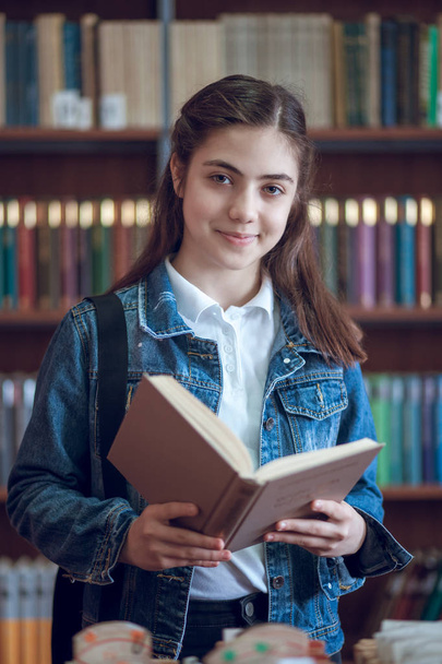красива школярка в бібліотеці читає книгу
 - Фото, зображення