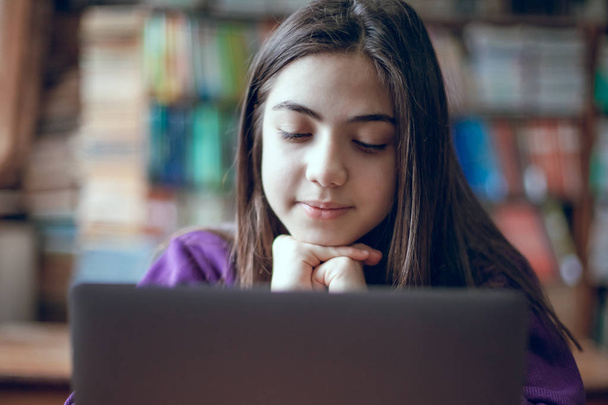 красива школярка навчається в шкільній бібліотеці за допомогою ноутбука
 - Фото, зображення