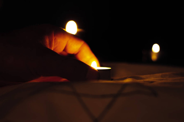 Symboli muistoksi juutalaisten kynttilöiden kansanmurhan uhreista, jotka palavat Daavidin tähden yllä mustalla taustalla surun päivänä. Holokaustin uhrien muistopäivä
 - Valokuva, kuva