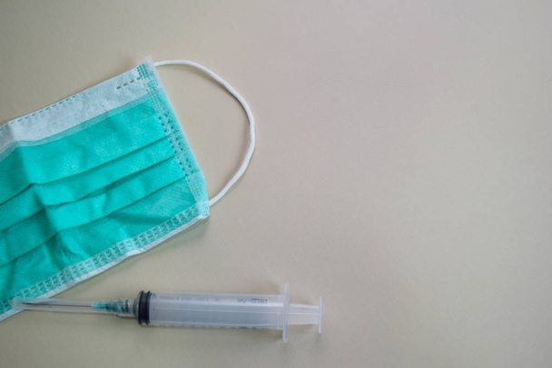 Close up protective face green mask and syringe isolated on brown background - Photo, Image