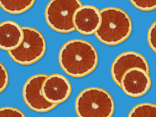 Patrón creativo hecho de naranjas rojas. vista superior del patrón de fruta colorida de rodajas de naranja roja fresca sobre fondo colorido púrpura
.  - Foto, Imagen