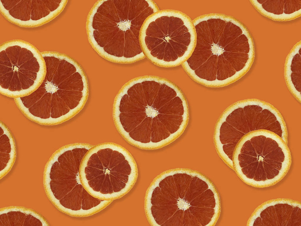 赤オレンジで作られた創造的なパターン。オレンジ色のカラフルな背景に新鮮な赤いオレンジ色のスライスのカラフルなフルーツパターンのトップビュー.  - 写真・画像