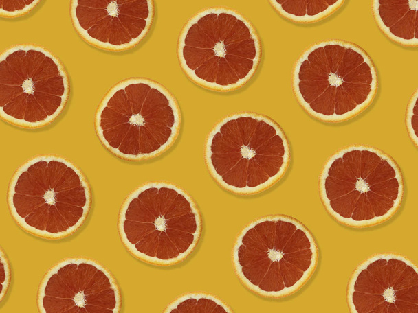 Kreatywny wzór wykonany z czerwonych pomarańczy. Widok z góry kolorowy wzór owoców świeżych czerwonych plasterków pomarańczy na pomarańczowym kolorowym tle.  - Zdjęcie, obraz