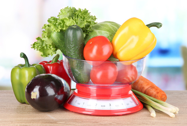 Fresh vegetables in scales on table in kitchen - Fotó, kép