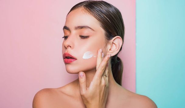 Taking good care of her skin. Beautiful woman spreading cream on her face. Skin cream concept. Facial care for female. Keep skin hydrated regularly moisturizing cream. Fresh healthy skin concept - Foto, afbeelding
