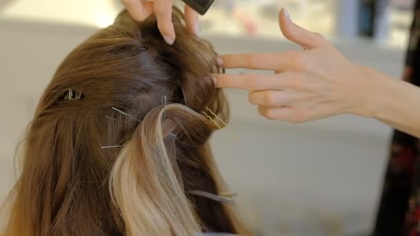 Женщина фиксирует прическу на каштановых волосах в салоне
 - Кадры, видео