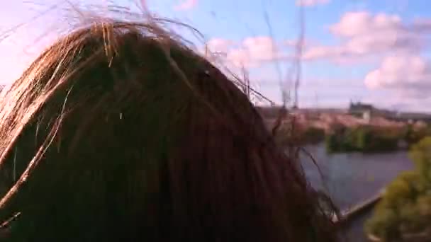 The wind blows the brown hair of a girl who watches with binoculars to the entire old city of Prague, on the roof of a dancing house. At the end of the camera comes close to the lens. - Footage, Video