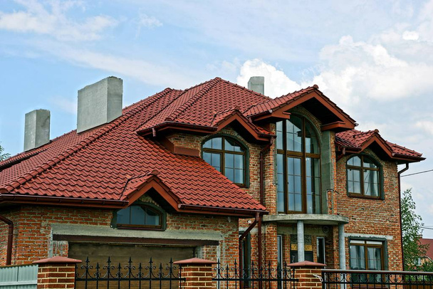 Parte de uma casa de tijolo com um telhado de azulejos vermelhos
 - Foto, Imagem