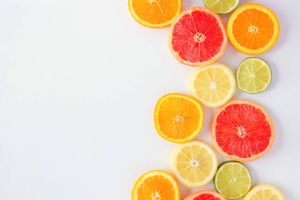 Kleurrijke fruit kant rand van verse Citrus plakjes. Bovenaanzicht, platte lay-out over een witte achtergrond met Kopieer ruimte. - Foto, afbeelding