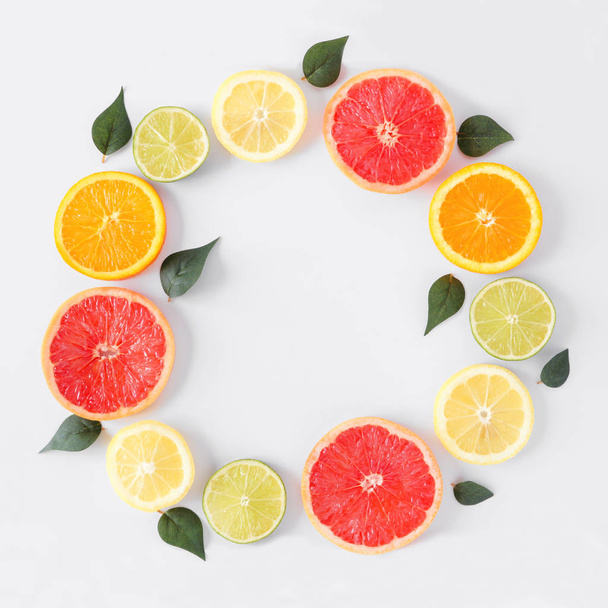 Colorful fruit circle frame of fresh citrus slices with leaves. Top view, flat lay over a white background with copy space. - Photo, Image