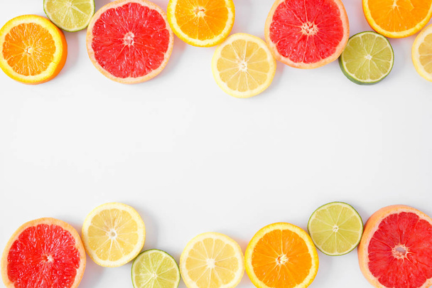 Barvité ovocné dvojité ohraničení čerstvých výřezů citrusových plodů. Pohled shora, plochá plocha nad bílým pozadím s prostorem pro kopírování. - Fotografie, Obrázek