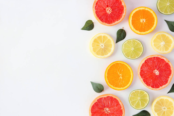 Kleurrijk fruit frame van verse Citrus plakjes met bladeren. Bovenaanzicht, platte lay-out over een witte achtergrond met Kopieer ruimte. - Foto, afbeelding