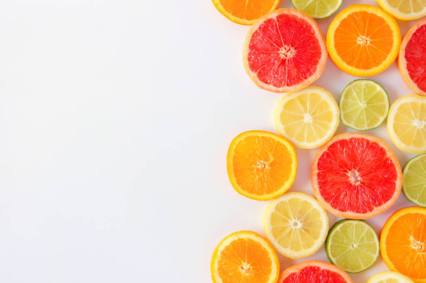Colorful fruit side border of fresh citrus slices. Top view, flat lay over a white background with copy space. - Fotografie, Obrázek