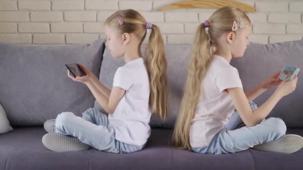 Twins in quarrel playing games on smartphones - Felvétel, videó