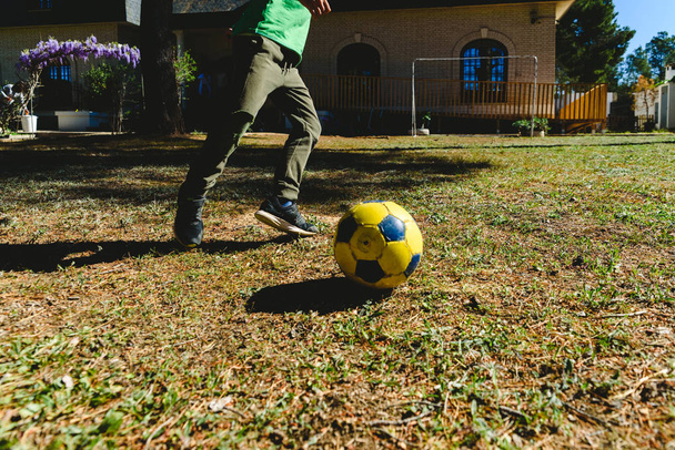 Child playing with a soccer ball in the yard of his house in the - Фото, изображение