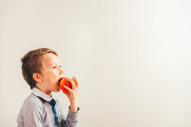 Niño feliz mordiendo una manzana sabrosa, aislado sobre fondo blanco f
 - Foto, imagen