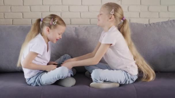 Twins take away the smartphone from each other - Materiał filmowy, wideo