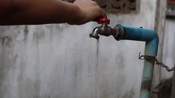 Jonge hand schakelt langzaam stromende oude waterkraan uit om water te besparen - bespaar waterconcept - Video