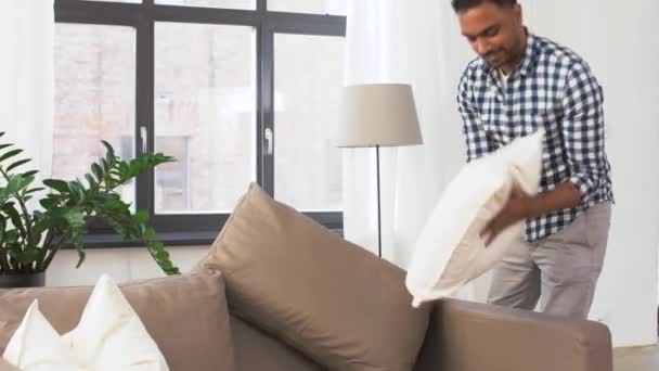 indian man arranging sofa cushions at home - Záběry, video