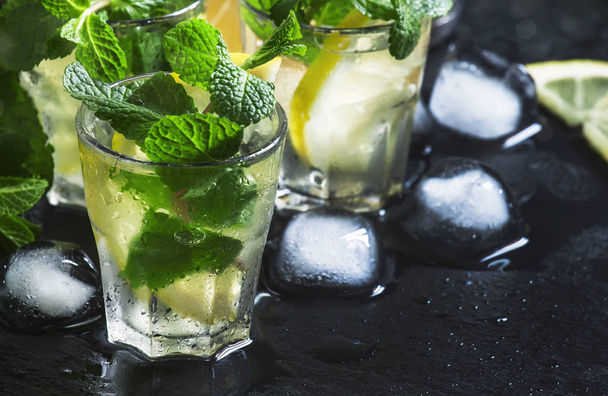 Alcoholic cocktail with vodka, mint tea, lemon juice, ice, sugar syrup and fresh peppermint, black background, selective focus - Zdjęcie, obraz
