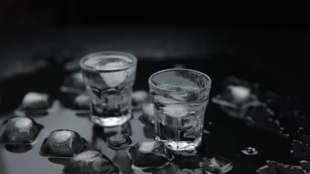 Добавить кубики льда, чтобы выстрел водки в стекло на черном фоне. Алкогольный напиток
 - Кадры, видео