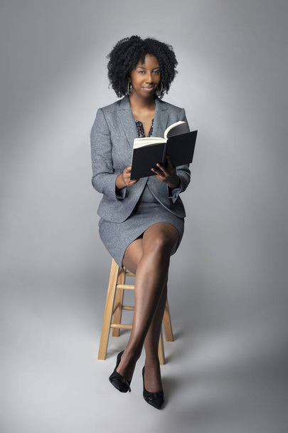 Black female author posing with a book in a studio for a portrait.  She looks like a teacher or a writer.  The image depicts education literacy and African American Studies.  - Fotografie, Obrázek