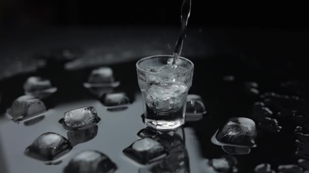 Echando vodka en un vaso. Fondo negro. Verter la bebida alcohólica
 - Metraje, vídeo