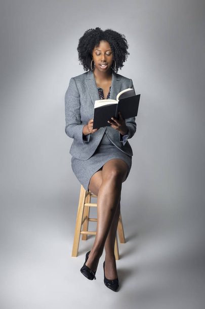 Черная женщина-автор позирует с книгой в студии для портрета. Она похожа на учителя или писателя. На рисунке изображена образовательная грамотность и афроамериканские исследования.
.  - Фото, изображение