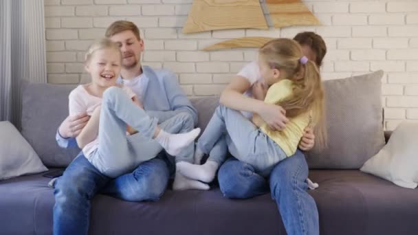 Parents tickling daughters on sofa - Imágenes, Vídeo