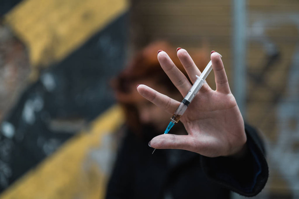 Κρατήστε τη σύριγγα στο χέρι σε διαμαρτυρία-ναρκομανής νεαρή κοκκινομάλλα γυναίκα σκέφτεται το νόημα της ζωής-κατάθλιψη και άγχος - Φωτογραφία, εικόνα