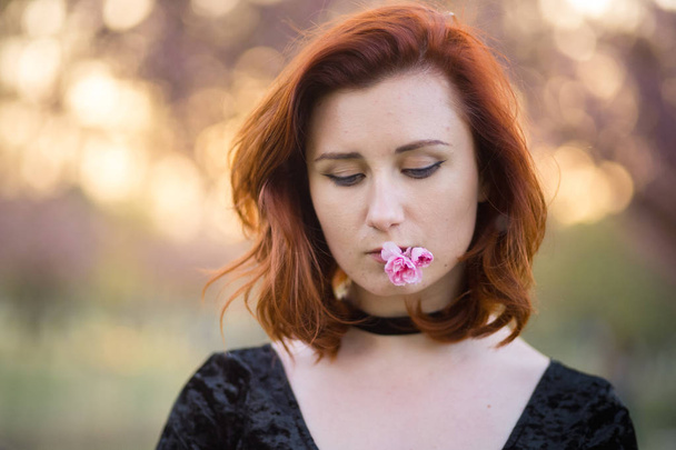 Face portrait close up - Happy young travel dancer woman enjoying free time in a sakura cherry blossom park - Caucasian white redhead girl - Dressed black chocker, black dress and black golfs - Foto, afbeelding