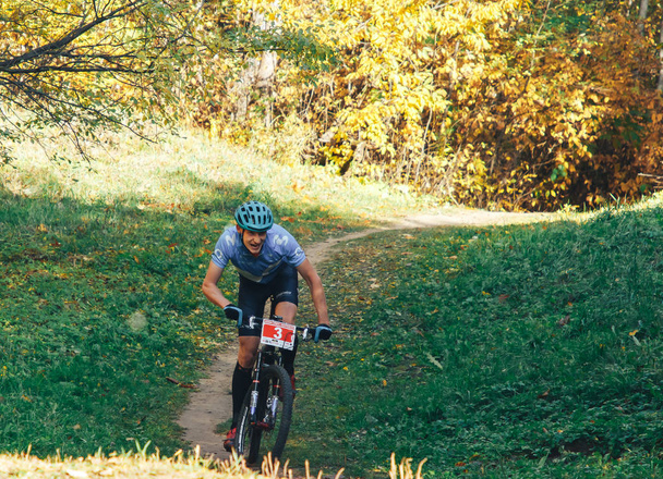 14 Ekim 2018, Minsk, Belarus. 2018 Olimpik Kros Kupası XCO Medvezhino Bisikletçi güzel sonbahar ormanı patikası boyunca bisiklet sürüyor. - Fotoğraf, Görsel