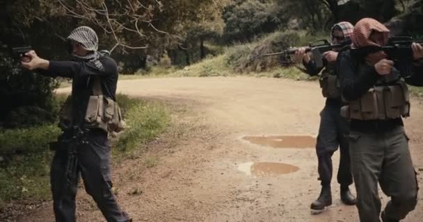 Team van gewapende terroristen patrouilleren een bosgebied tijdens gevechten - Video
