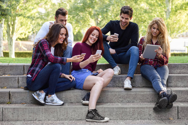Young people using smartphone and tablet computers outdoors - Foto, Imagem