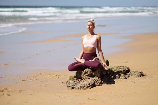 Femme blonde caucasienne pratiquant le yoga à la plage
 - Photo, image