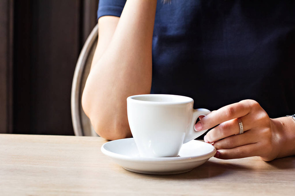 A cup of coffee in a cafe and a girl's hands. - Фото, изображение