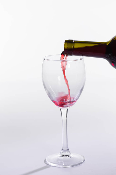 Vörösbor öntés palackból nagy pohár fehér alapon - Fotó, kép