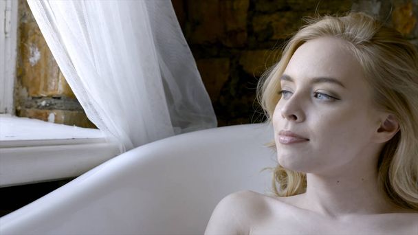 バスルームでポーズをとる朝の美しい女の子セクシーなブロンド。アクション。朝風呂に横たわる若いブロンドの女性 - 写真・画像