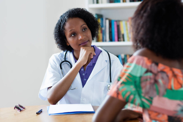 Αφρικανική Αμερικανίδα γυναίκα γιατρός ακούγοντας ασθενή - Φωτογραφία, εικόνα