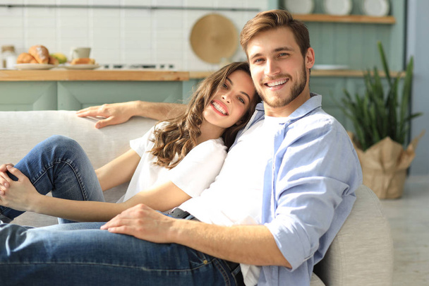 Portrait of cute young couple sitting in sofa. - Foto, imagen